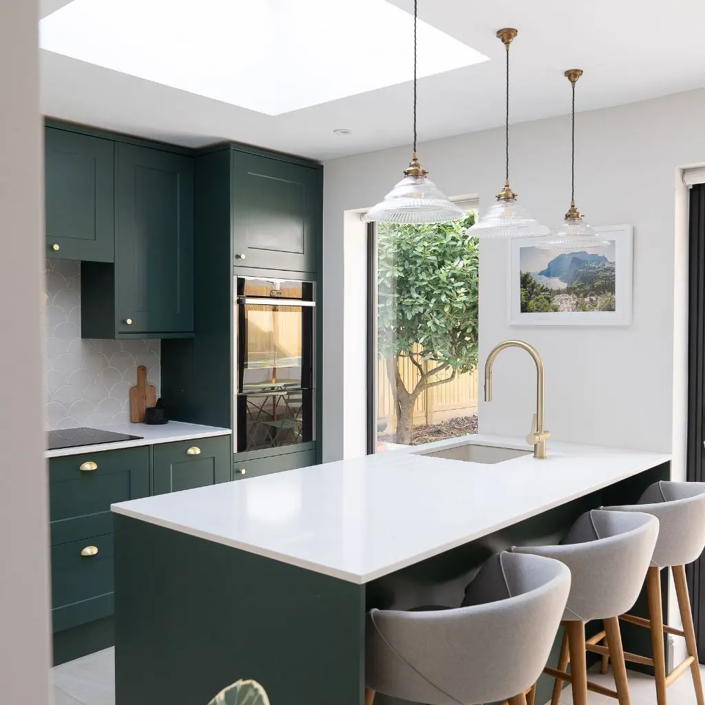 Aménagement intérieur d’une cuisine verte et blanche avec éléments en laiton