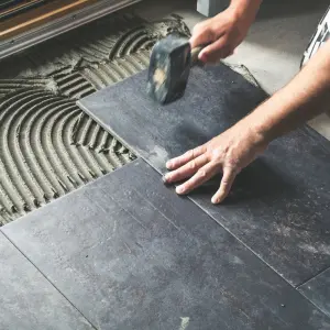 Artisan en train de poser du carrelage sur un sol intérieur