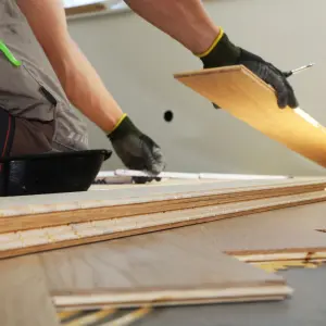 Artisan posant un parquet en bois sur un sol intérieur